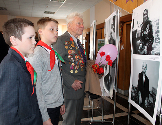 Один из участников фотовыставки "Журавли" ветеран войны Виктор Демьянович Терещенко рассказывает пионерам о героях былых времен